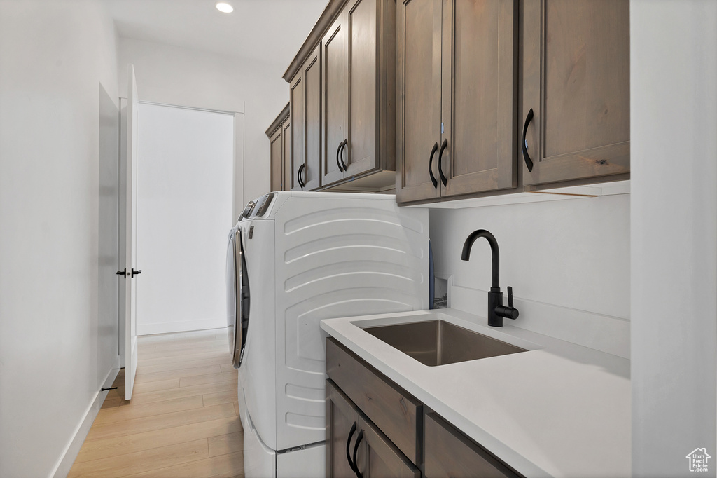 Laundry room with cabinet space, washer and clothes dryer, light wood-type flooring, and recessed lighting