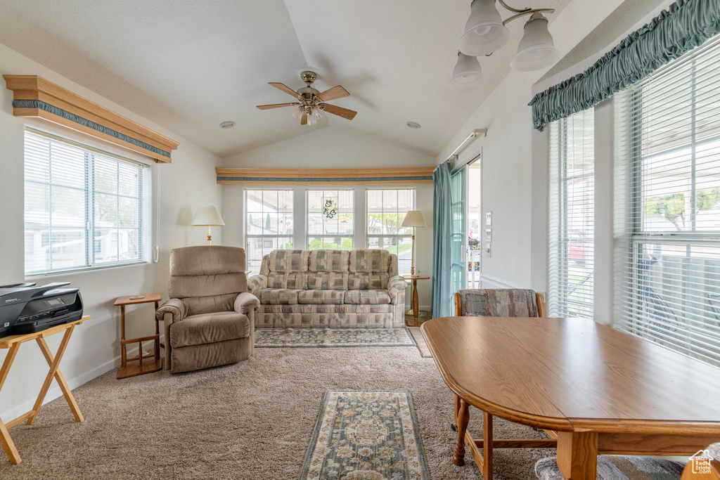 Carpeted living room with baseboards, lofted ceiling, ceiling fan, and a healthy amount of sunlight
