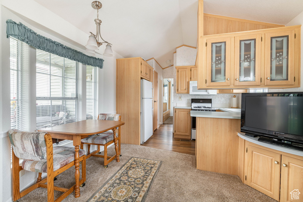 Kitchen with light countertops, light brown cabinetry, vaulted ceiling, and white appliances