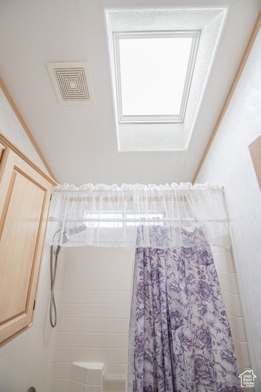Bathroom with visible vents, shower / bath combination with curtain, and a skylight