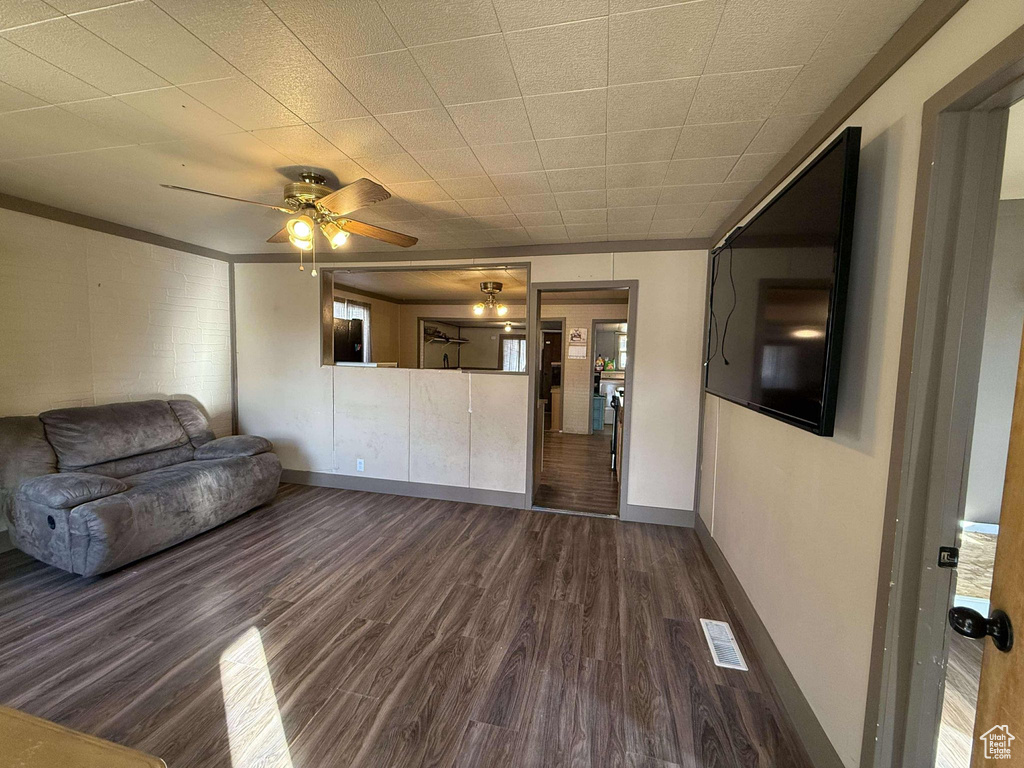 Unfurnished living room featuring dark hardwood / wood-style floors, ceiling fan, and ornamental molding