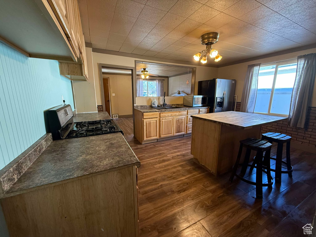 Kitchen featuring sink, a breakfast bar area, an inviting chandelier, stainless steel appliances, and dark hardwood / wood-style flooring