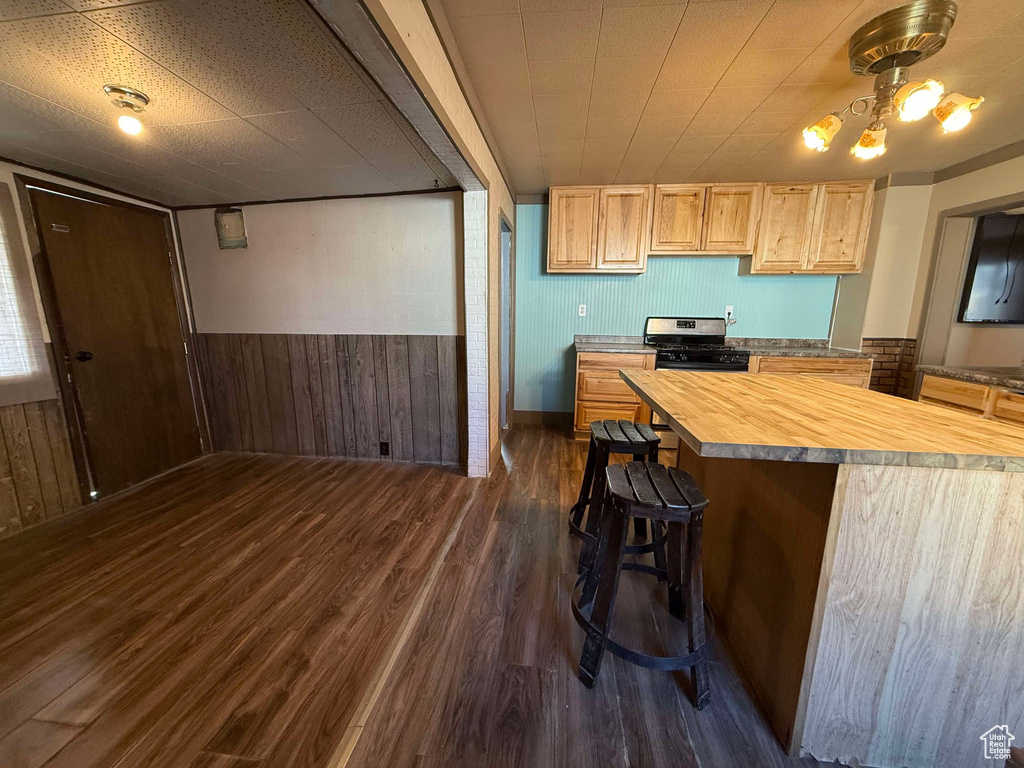 Kitchen featuring gas stove, butcher block countertops, wood walls, light brown cabinets, and dark hardwood / wood-style floors