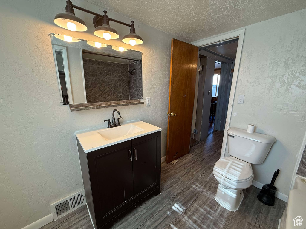 Bathroom featuring vanity, wood-type flooring, toilet, and a textured ceiling