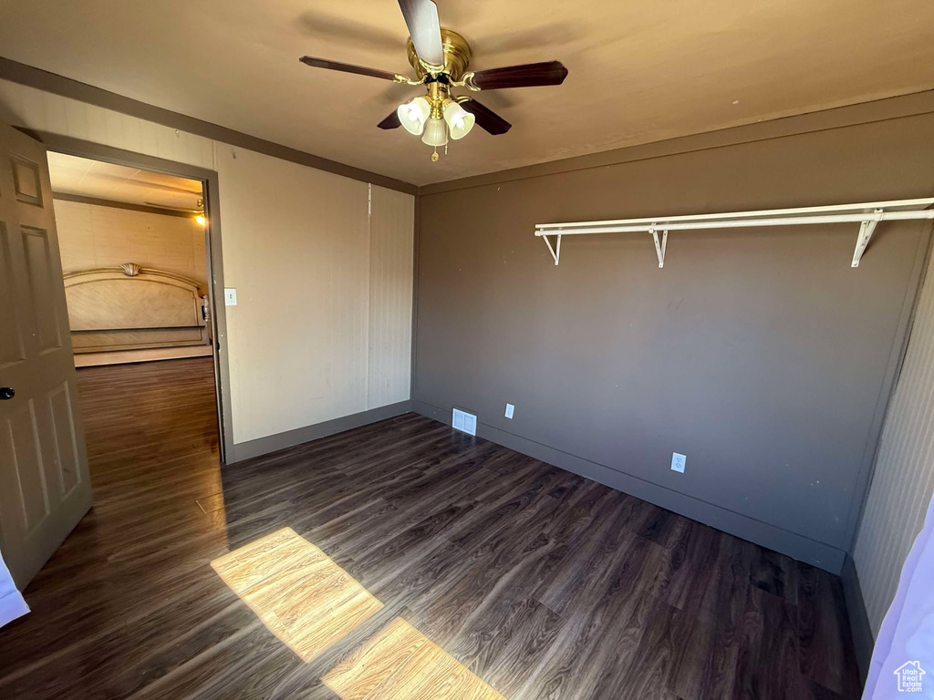 Unfurnished bedroom featuring dark hardwood / wood-style flooring, ceiling fan, and a closet