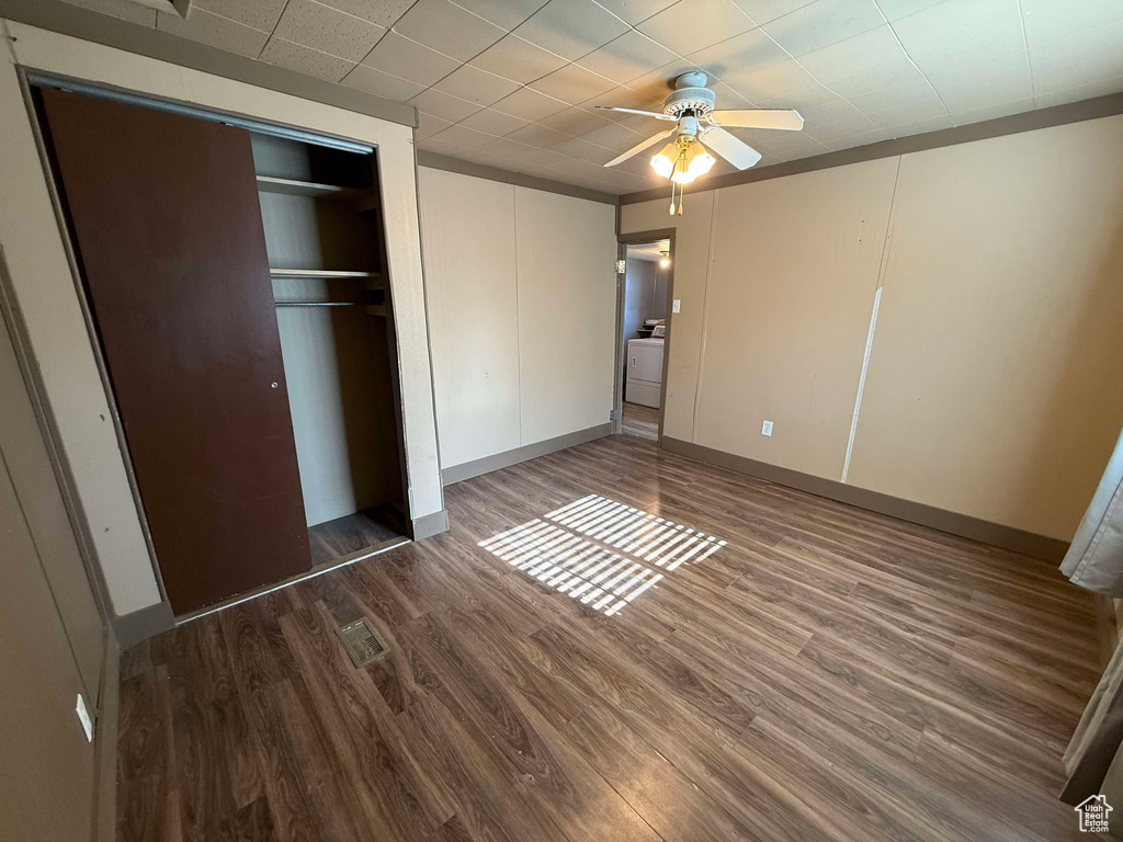 Unfurnished bedroom featuring washer / clothes dryer, dark wood-type flooring, a closet, and ceiling fan