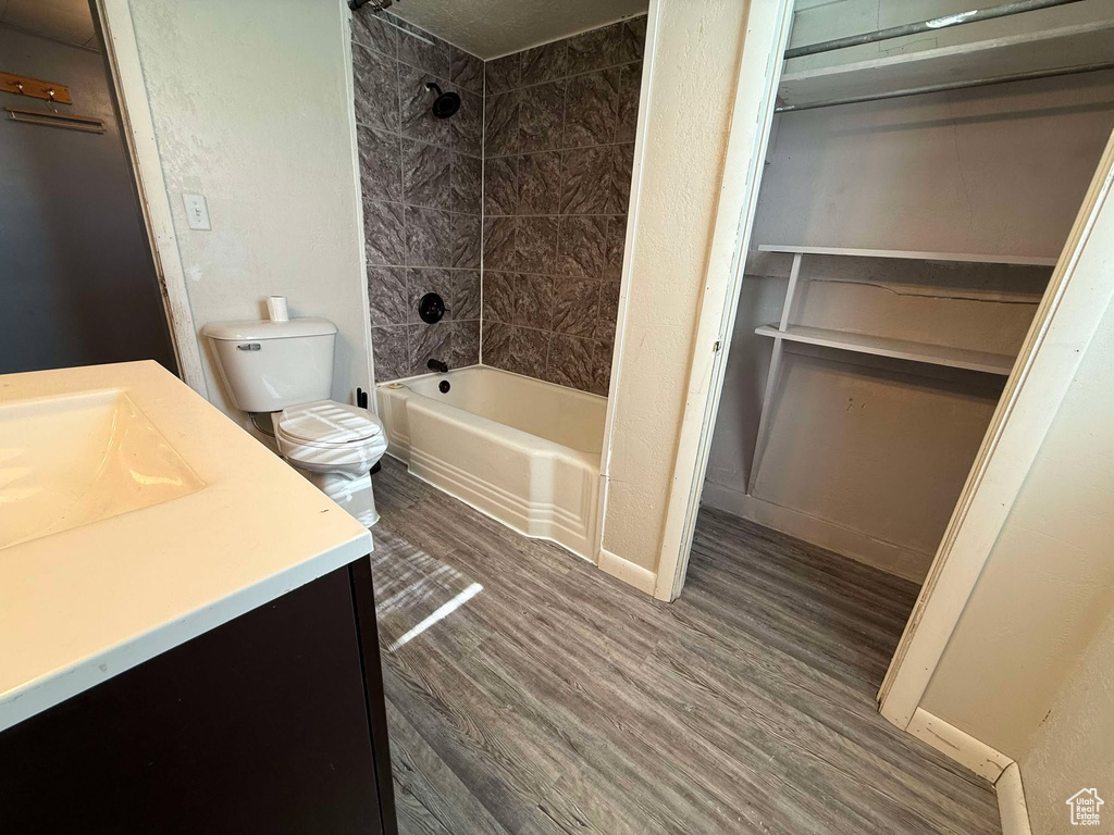 Full bathroom with vanity, hardwood / wood-style floors, toilet, and tiled shower / bath