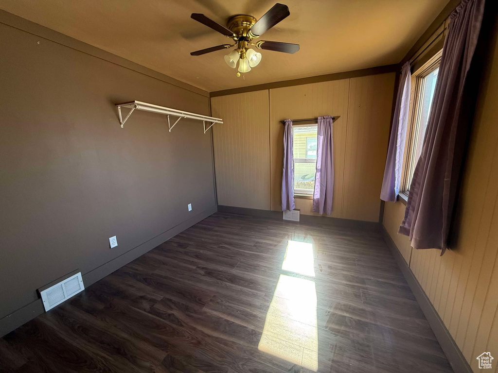 Empty room with crown molding, ceiling fan, and dark hardwood / wood-style flooring