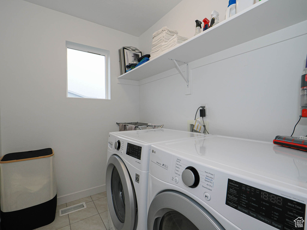 Laundry area featuring light tile patterned floors and washing machine and clothes dryer