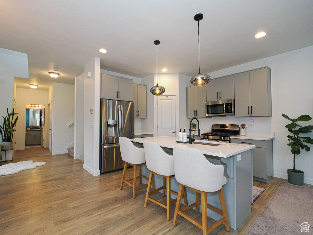 Kitchen with sink, stainless steel appliances, gray cabinetry, and light hardwood / wood-style floors