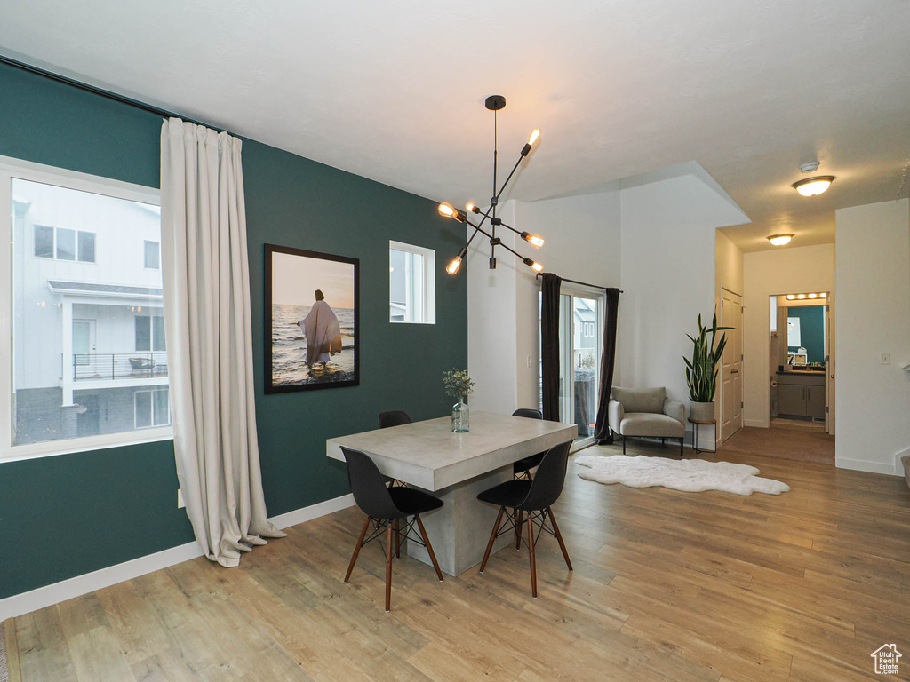 Dining space featuring a healthy amount of sunlight, light hardwood / wood-style floors, and a notable chandelier