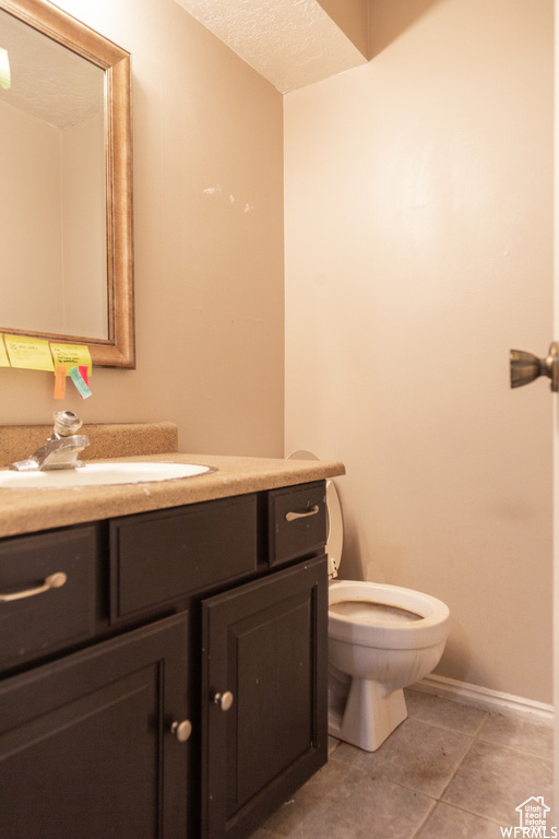 Bathroom with vanity, a textured ceiling, toilet, and tile patterned floors