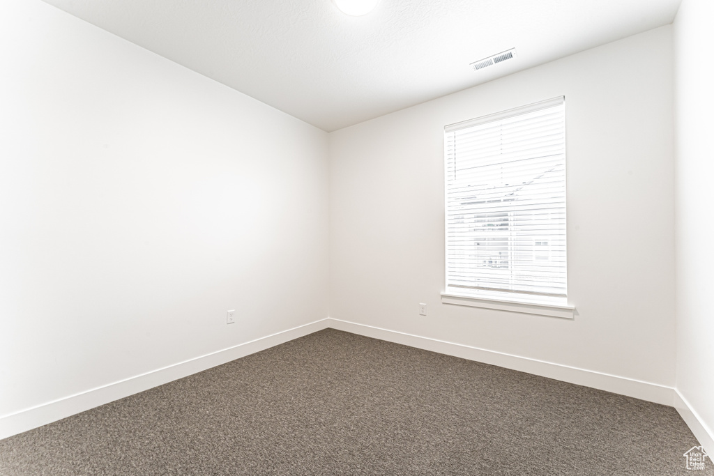 Empty room featuring dark carpet and baseboards
