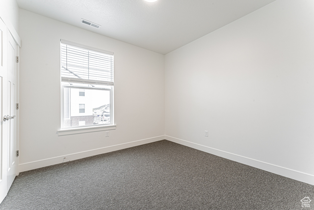Unfurnished room featuring baseboards and dark colored carpet