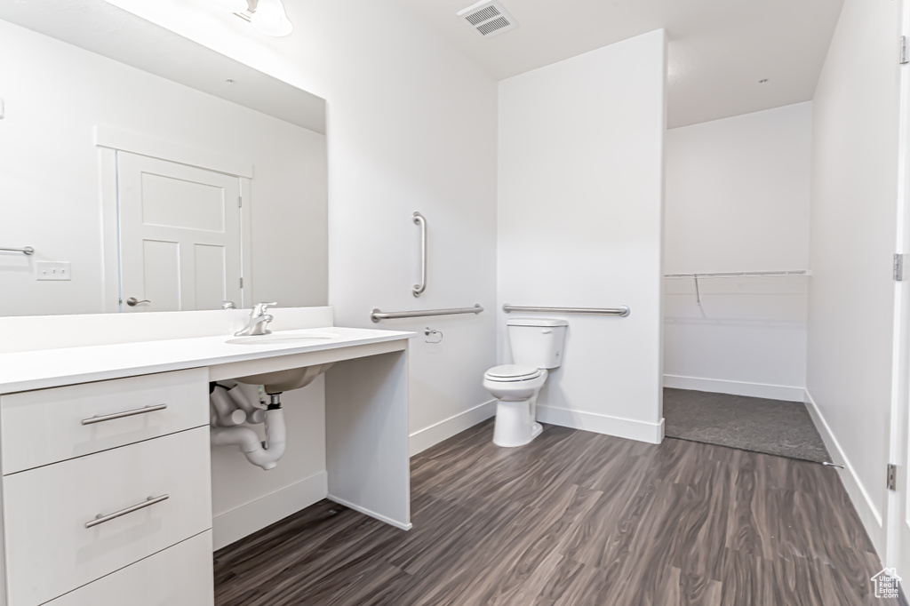 Bathroom featuring toilet, wood finished floors, and baseboards