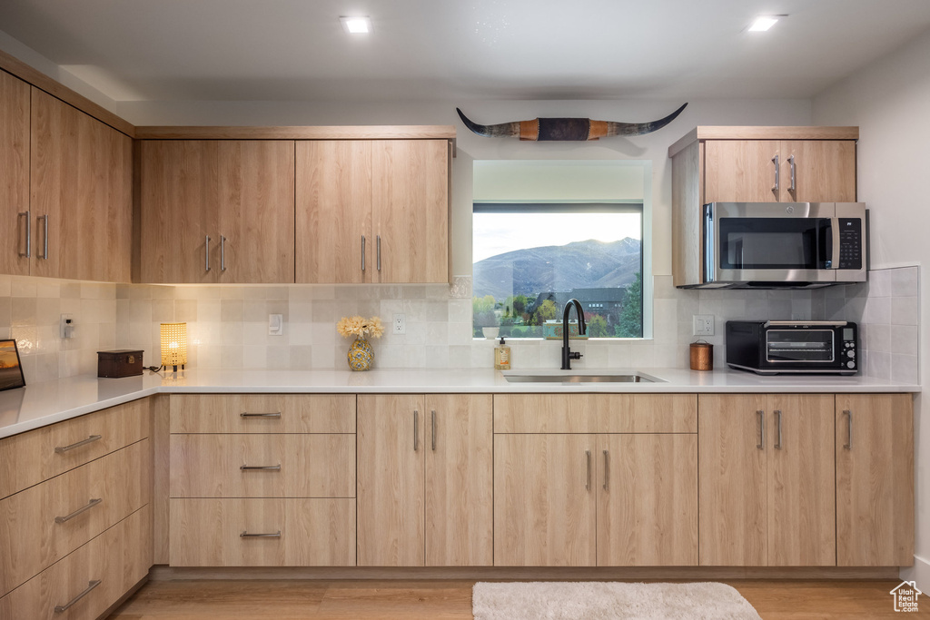 Kitchen with a mountain view, light brown cabinets, sink, and light hardwood / wood-style flooring