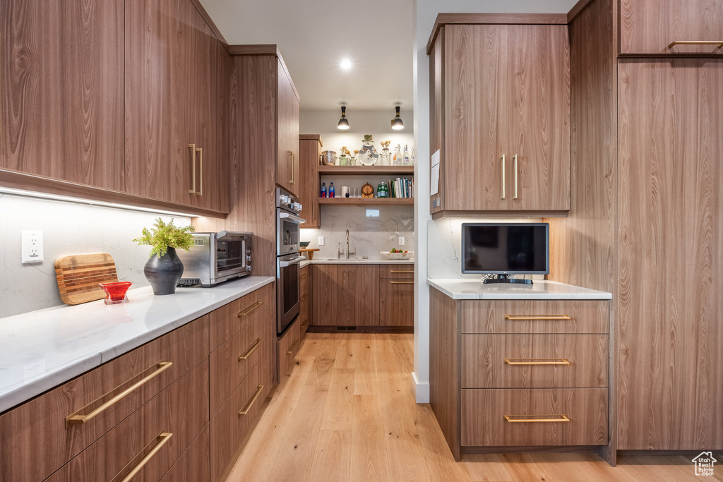 Kitchen featuring light wood-type flooring, double oven, and sink