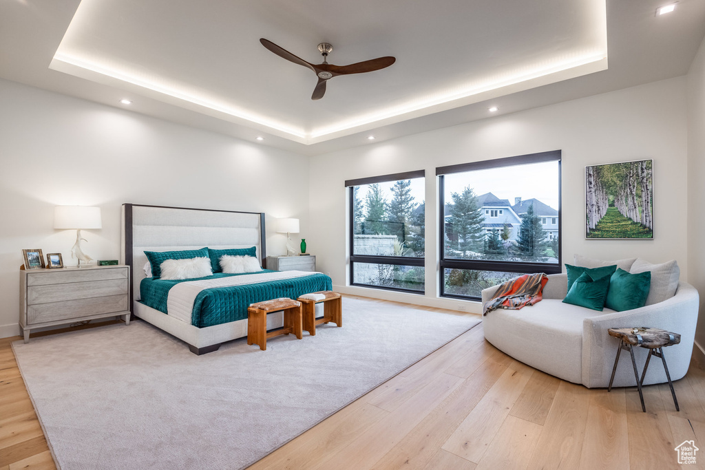 Bedroom featuring hardwood / wood-style flooring, a raised ceiling, and ceiling fan