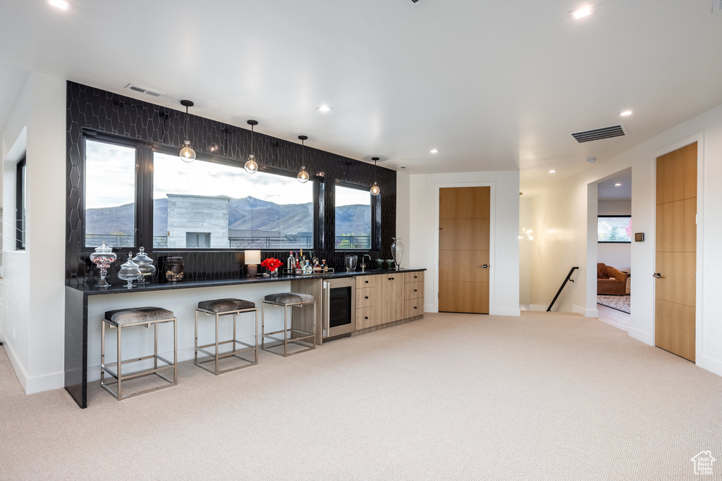 Kitchen featuring a mountain view, light colored carpet, decorative light fixtures, and beverage cooler