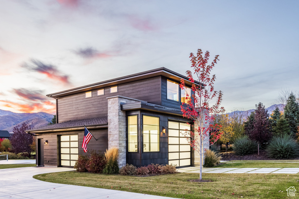 View of front facade featuring a mountain view, a yard, and a garage