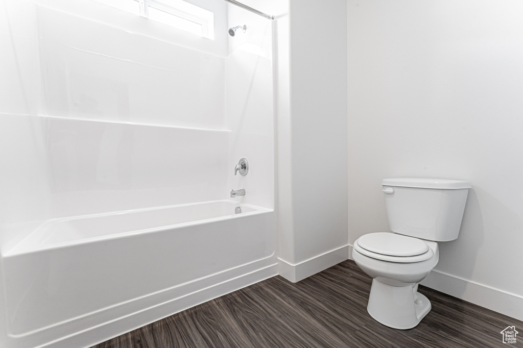 Full bath with baseboards, toilet, shower / bathtub combination, and wood finished floors