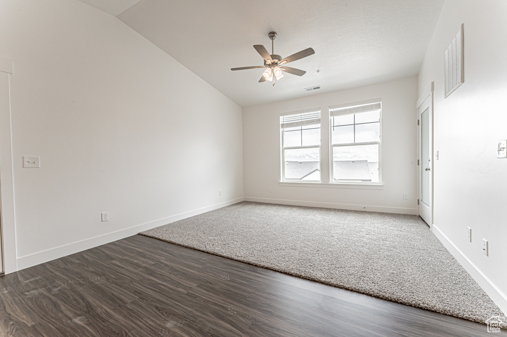 Empty room with lofted ceiling, a ceiling fan, wood finished floors, and baseboards
