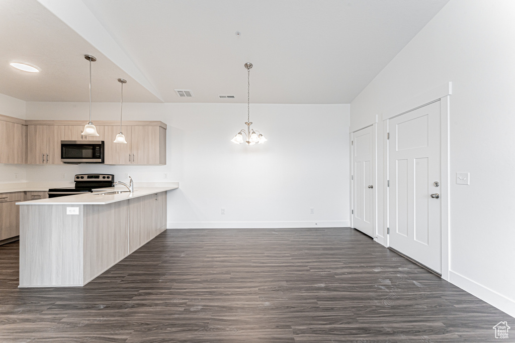 Kitchen with stainless steel appliances, a peninsula, a sink, light countertops, and light brown cabinetry