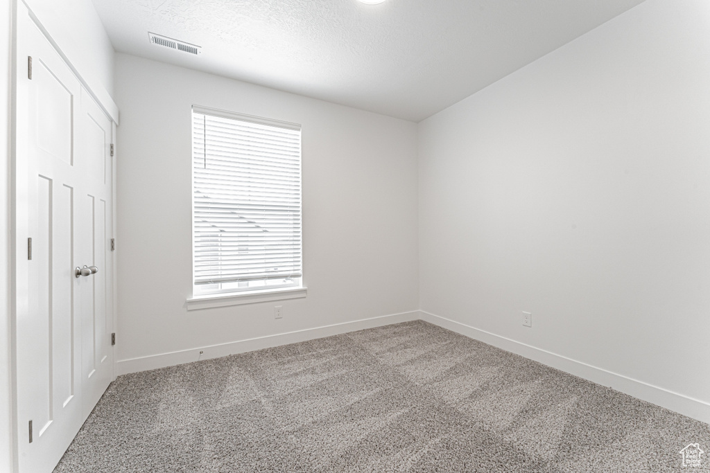 Unfurnished bedroom with carpet floors, baseboards, and a textured ceiling