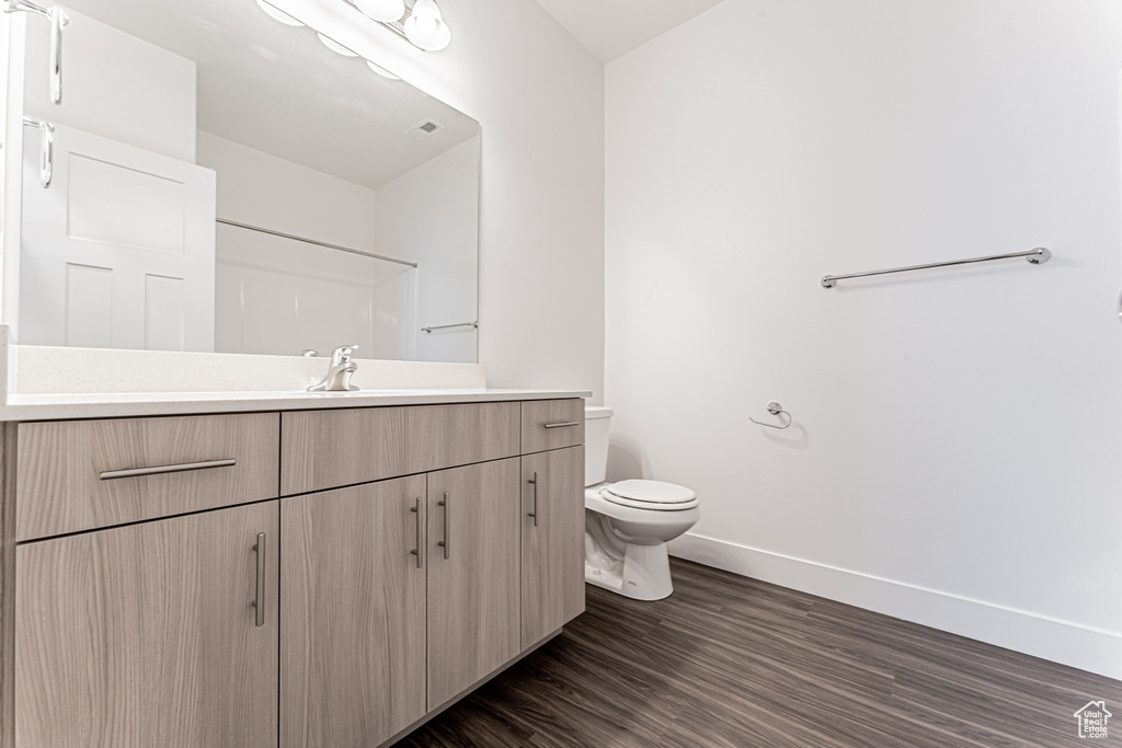 Full bathroom featuring baseboards, vanity, toilet, wood finished floors, and a shower