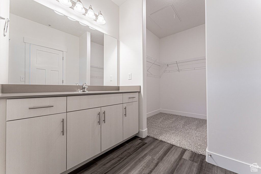 Bathroom with vanity, wood finished floors, a walk in closet, and baseboards