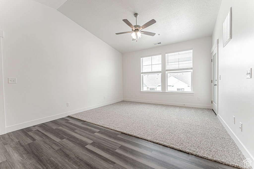 Empty room with ceiling fan, vaulted ceiling, wood finished floors, and baseboards