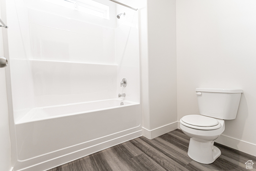 Full bathroom featuring baseboards, toilet, wood finished floors, and tub / shower combination