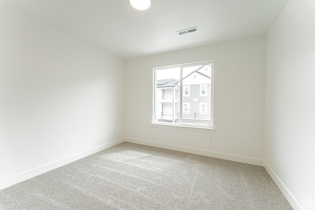 Spare room with light carpet, baseboards, and visible vents