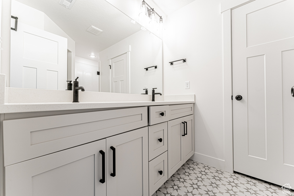 Bathroom featuring visible vents, baseboards, double vanity, tile patterned floors, and a sink