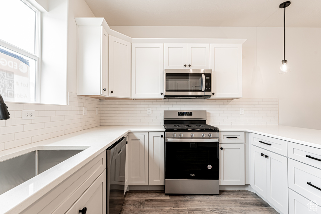 Kitchen with a sink, white cabinetry, stainless steel appliances, light wood-style floors, and decorative backsplash