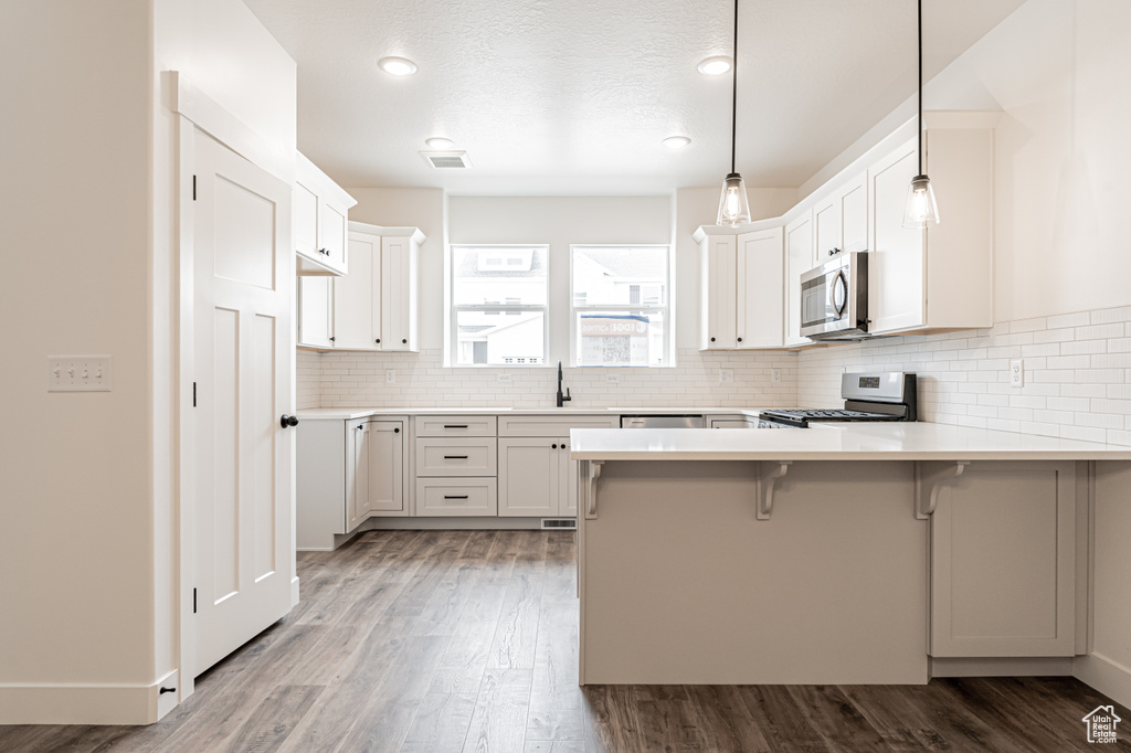Kitchen featuring a peninsula, a sink, appliances with stainless steel finishes, and wood finished floors