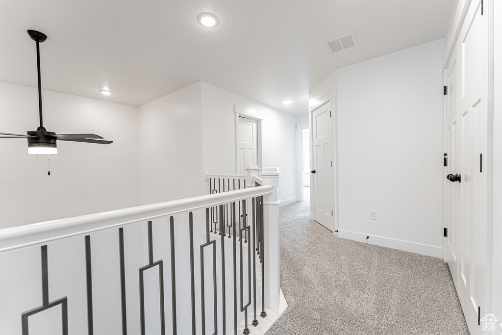 Corridor with an upstairs landing, light carpet, baseboards, visible vents, and recessed lighting