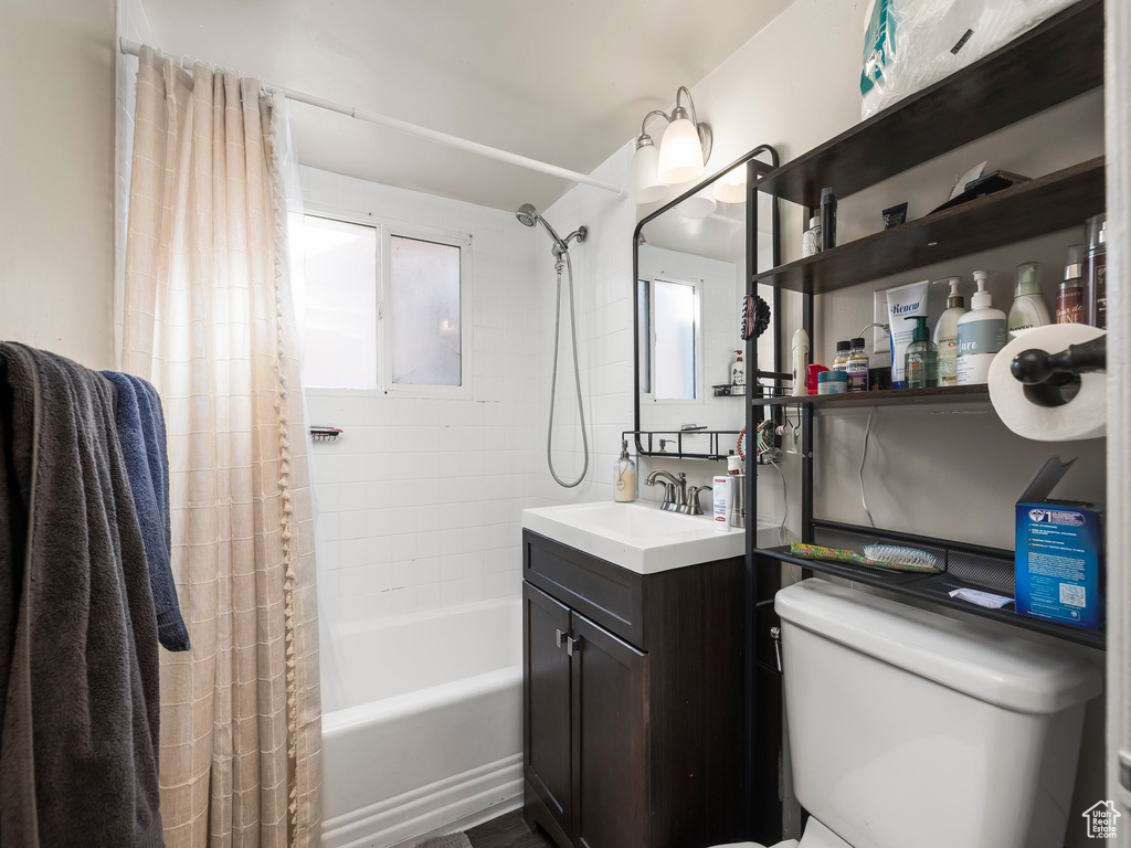 Full bathroom with vanity, a healthy amount of sunlight, toilet, and shower / bathtub combination with curtain