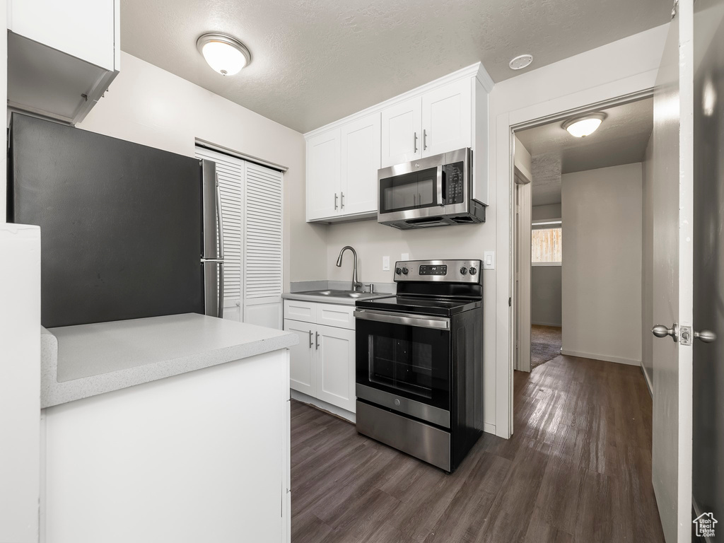 Kitchen featuring white cabinetry, sink, dark hardwood / wood-style flooring, a textured ceiling, and appliances with stainless steel finishes