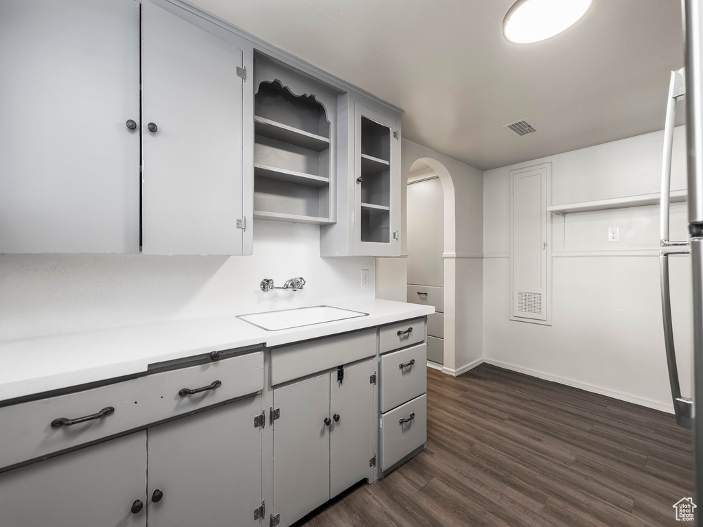 Kitchen with white cabinets, dark wood-type flooring, and sink