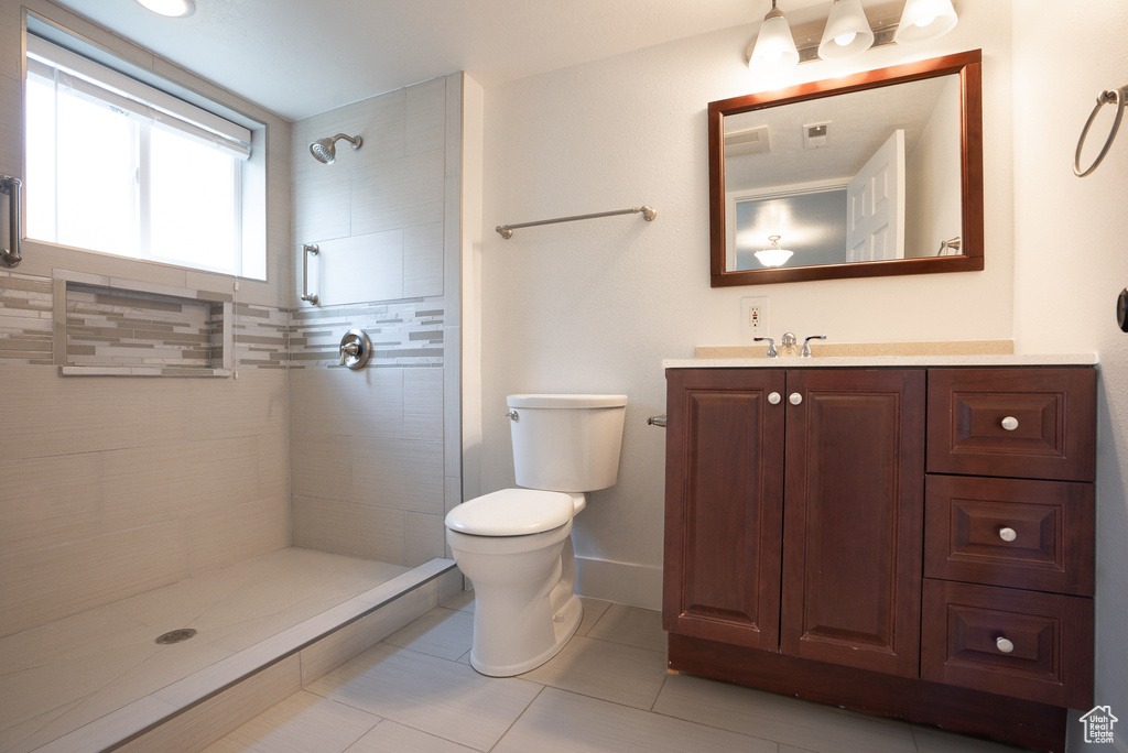 Bathroom with tile patterned flooring, vanity, toilet, and a tile shower