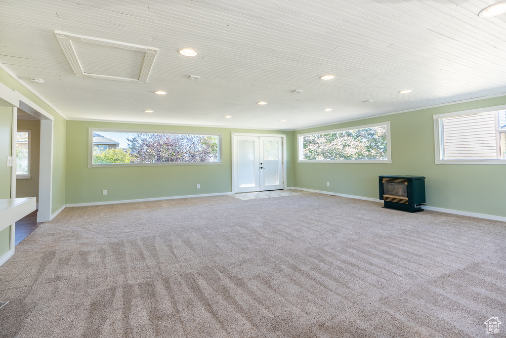 Unfurnished living room featuring a healthy amount of sunlight, a wood stove, and light carpet