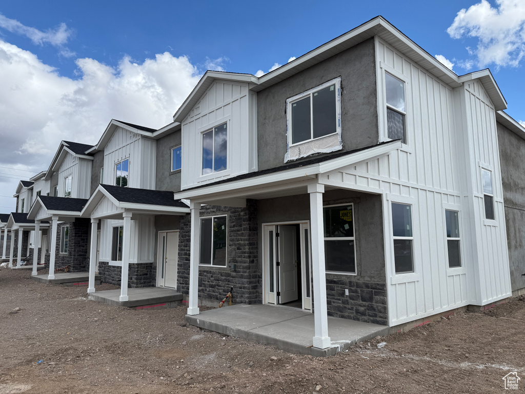 View of front of home with board and batten siding, covered porch, and stone siding