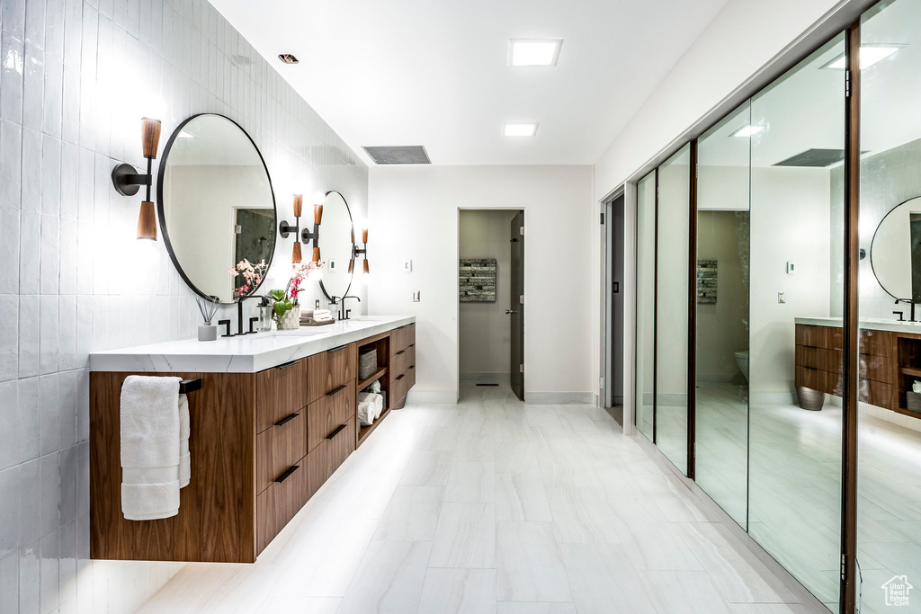 Bathroom with vanity, toilet, and tile walls