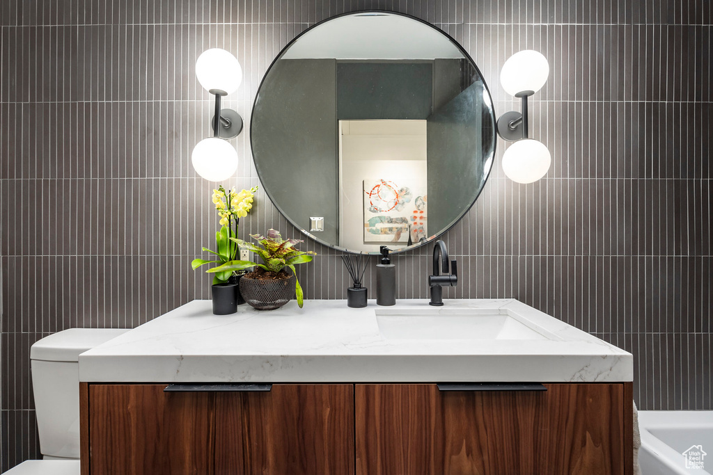 Bathroom with vanity, tile walls, and toilet