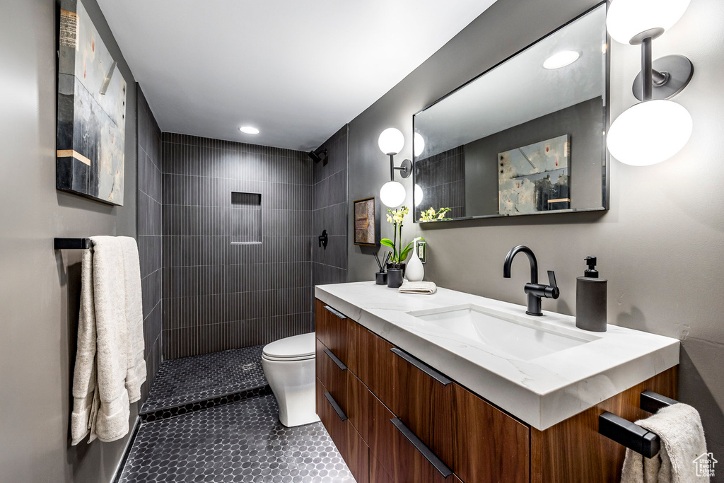 Bathroom featuring vanity, toilet, and tiled shower