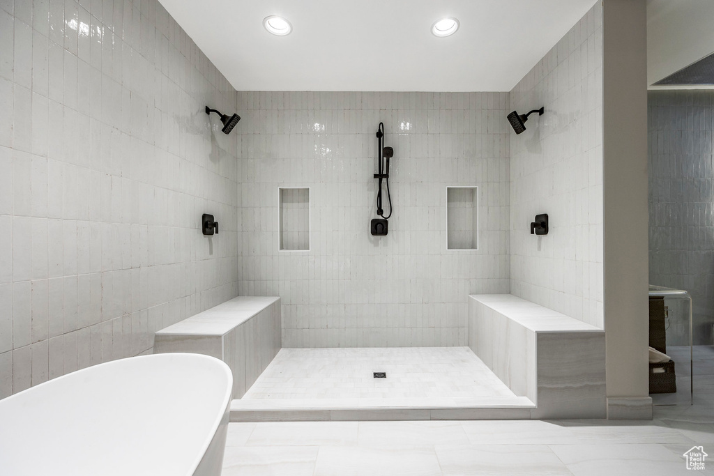 Bathroom featuring separate shower and tub and tile walls