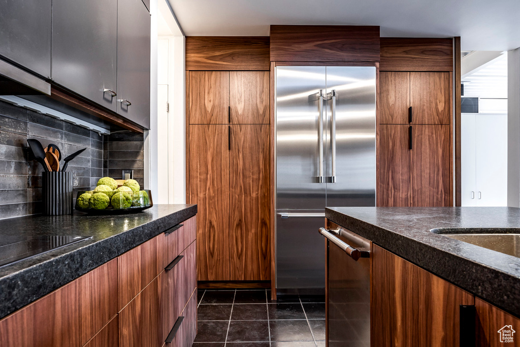 Kitchen featuring backsplash, dark tile patterned floors, and stainless steel appliances