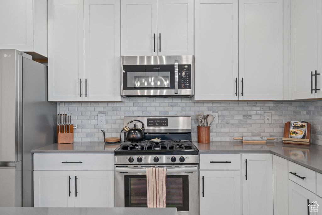 Kitchen with white cabinets, backsplash, and stainless steel appliances