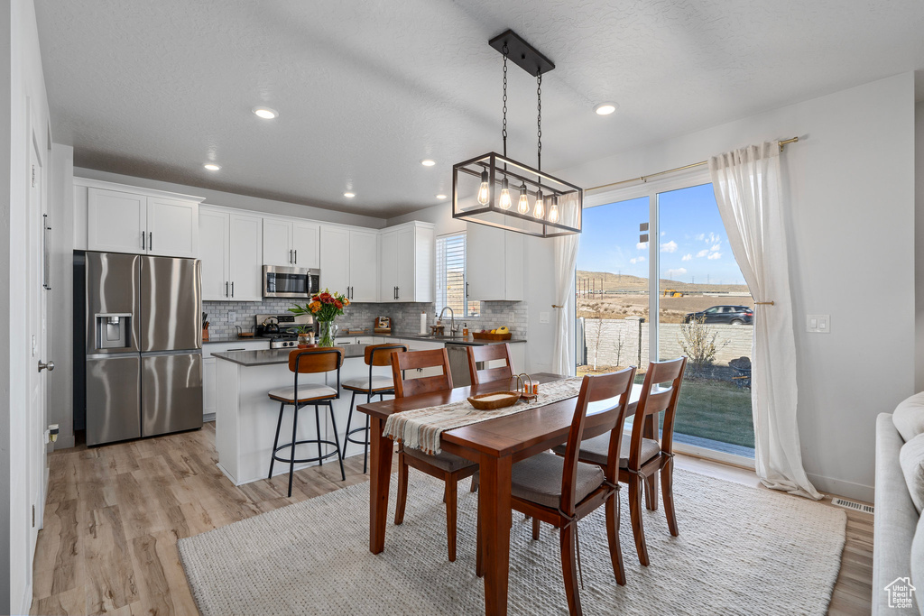 Dining area with light hardwood / wood-style flooring, a textured ceiling, and sink